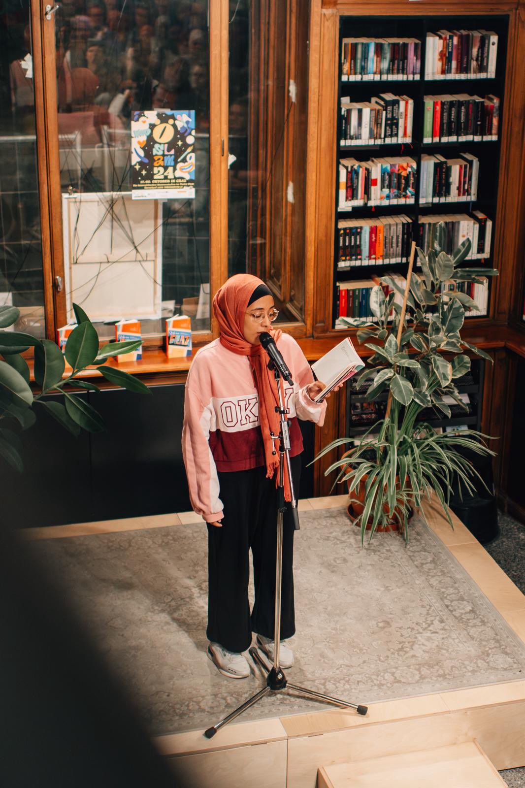 Mervat_Spoken Word Die Spoken Word Künstlerin Mervat liest auf der Bühne aus ihrem Notizbuch vor.