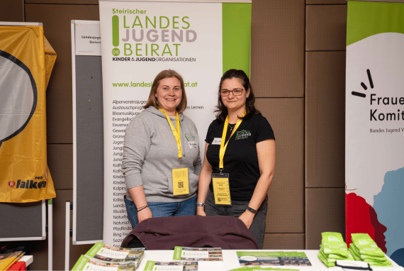 Dieses Bild zeigt zwei Vertreterinnen des Landesjugendbeirats Steiermark bei ihrem Stand auf der Vollversammlung der Bundesjugendvertretung.
