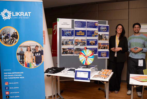Dieses Bild zeigt zwei Vertreter*innen von Likrat bei ihrem Stand auf der Vollversammlung der Bundesjugendvertretung.