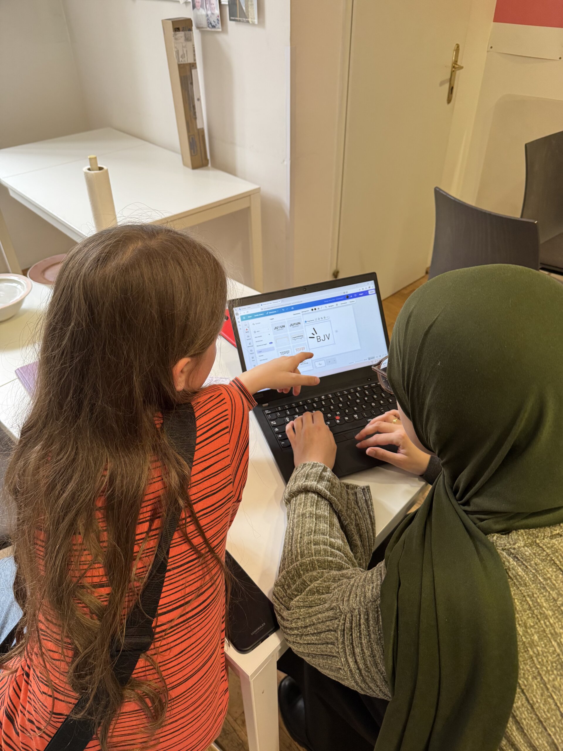 Eine Frau und ein Junge sitzen vor dem Laptop und erstellen eine Präsentation.