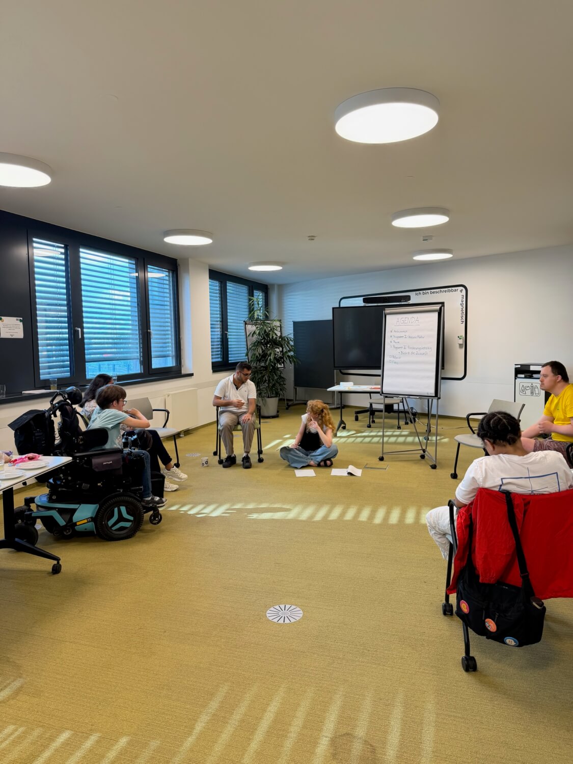 Die Mitglieder des Inklusionsbeirats sitzen im Kreis und diskutieren.