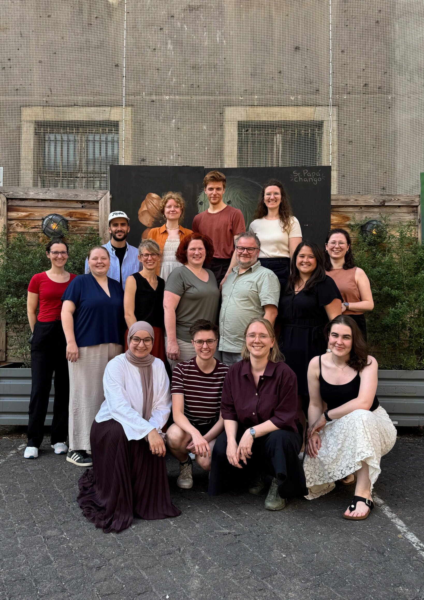 Männer und Frauen stehen und hocken bei der Studienreise in Berlin lächelnd beieinander.