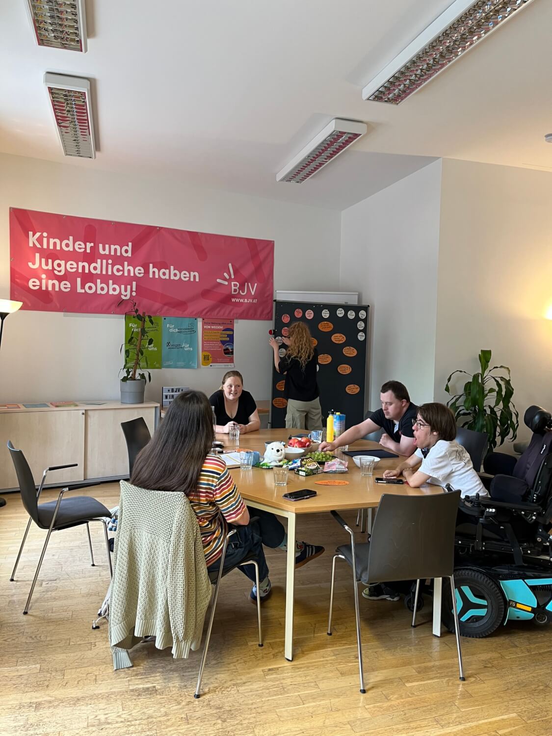 Die Beiratsmitglieder sitzen in einer Tischgruppe und diskutieren. Argumente werden aufgeschrieben und auf einer Pinnwand festgehalten.